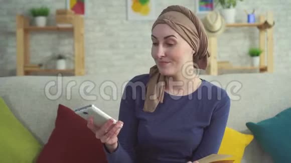 阳性的年轻女性癌症患者化疗后戴着围巾打电话视频的预览图