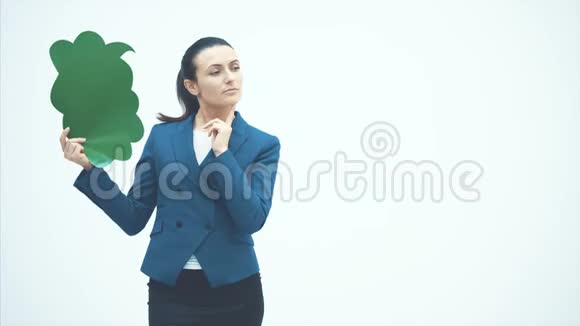 一位漂亮的年轻老师手里拿着一个绿色的弹出指着它微笑着老师站在白色的背景上视频的预览图
