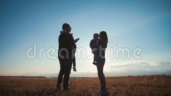 一个剪影幸福的年轻家庭日落时幸福的家庭父亲母亲和两个孩子玩得很开心视频的预览图