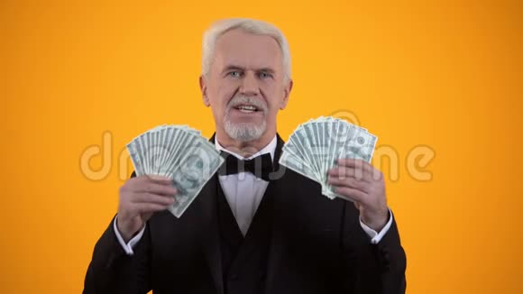 富有的老人穿着西装挥舞着美元微笑着生意成功视频的预览图