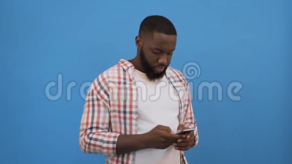 输入信息黑人男子在手机上打字被隔离在蓝色4K上视频的预览图