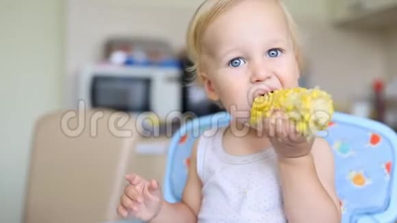 可爱可爱的白人金发男孩坐在厨房的高脚椅上享受着美味的甜煮玉米快乐视频的预览图