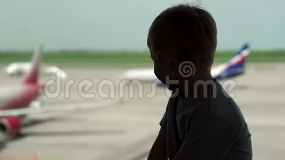小男孩的剪影靠近机场的窗户他看着飞机视频的预览图