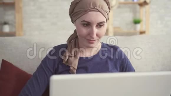 化疗后戴头巾的患癌阳性的年轻女性使用笔记本电脑视频的预览图