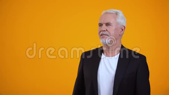穿西装的快乐老人在橙色背景下享受着愉快的香气视频的预览图