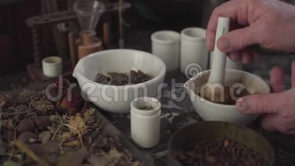 配有干花和老式化学容器的桌子老男性白种人用手研磨粉末视频的预览图