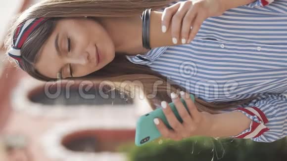 圣经录像漂亮的年轻女孩带着头巾穿着时髦的条纹连衣裙用她的智能手机滚动看上去视频的预览图