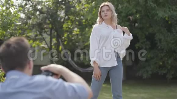 拍摄的后台专业摄影师拍摄穿白色衬衫和牛仔裤的优雅女人的照片视频的预览图