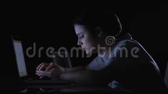 在黑暗中工作的女性自由职业者看着女孩的照片和关闭笔记本电脑视频的预览图