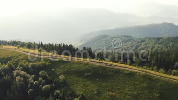 夫妇正骑着四人自行车鸟瞰喀尔巴阡山公路森林景观夏日视频的预览图