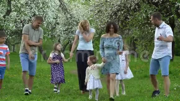 两个年轻的家庭日复一日地带着疲惫的孩子果树盛开视频的预览图