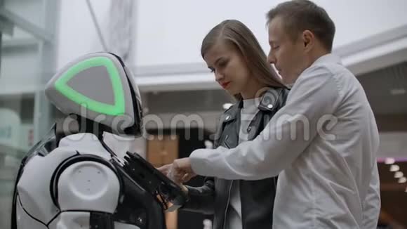两个人一男一女与机器人交流用手按屏幕上的机器人一个机器人助手视频的预览图