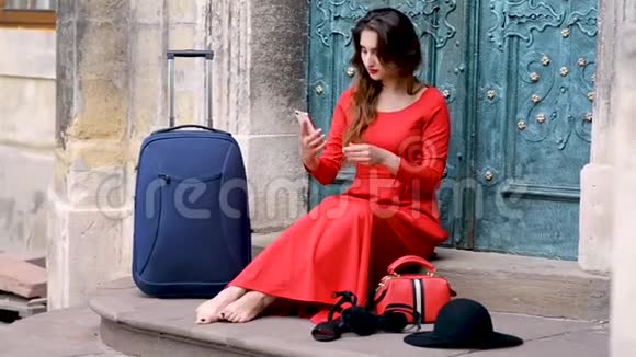 美丽的旅游女孩带着手提箱在户外的楼梯上自拍视频的预览图