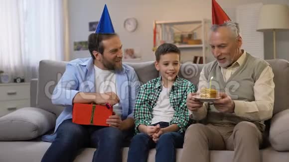 爷爷和爸爸在b日祝贺小男孩送礼物盒和蛋糕视频的预览图