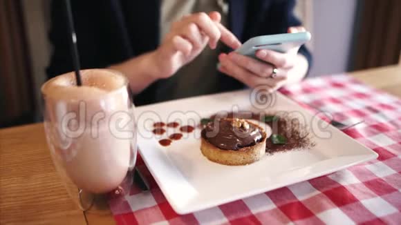 时髦的女孩在咖啡馆的社交媒体上发短信分享她的食物照片浅自由度视频的预览图