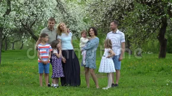 春天花园的家庭带孩子的父母在镜头前摆姿势视频的预览图