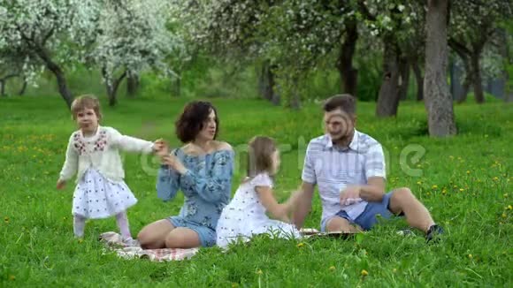 春天有两个女儿的年轻父母在公园的格子花里休闲视频的预览图
