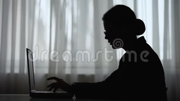 商务女性在笔记本电脑上打字稍作停顿集中注意力的剪影视频的预览图
