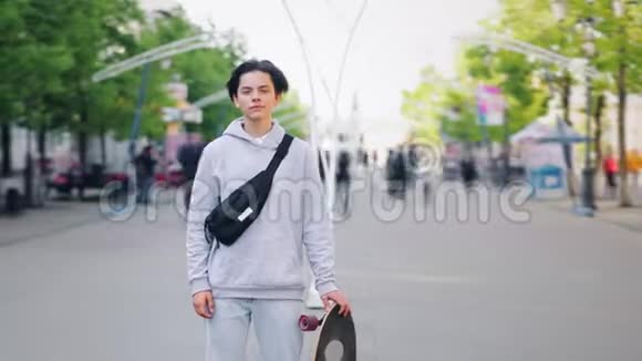 一个人站在大街上的时髦少年滑板手的时光流逝画像视频的预览图