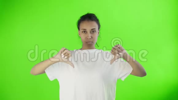 穿着白色T恤的漂亮少女拇指朝下双手放在色键背景上视频的预览图
