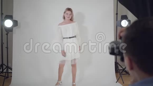 拍摄的后台专业摄影师为站在白色的迷人优雅女人拍照视频的预览图