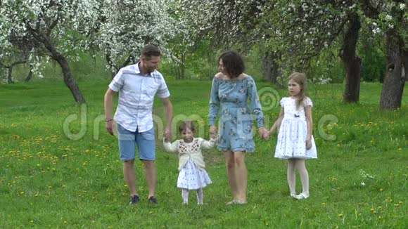 父母和两个女儿在盛开的春天花园慢镜头视频的预览图