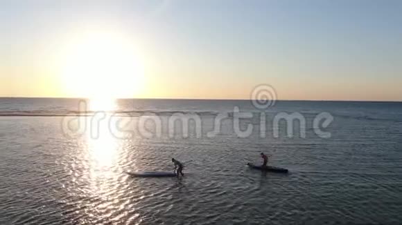 两个手里拿着桨的妇女在海里推冲浪板视频的预览图