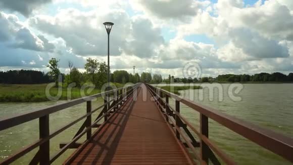 连接两个湖岸的人行桥带着相机行走在人行天桥上视频的预览图
