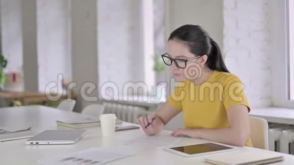 雄心勃勃的年轻女设计师在办公室的文件上写作视频的预览图