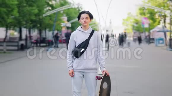 年轻滑板运动员站在户外的街道上与滑板的距离缩短视频的预览图