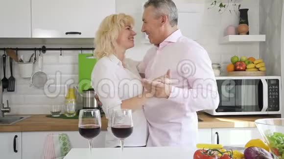 快乐的退休夫妇在舒适的厨房跳舞视频的预览图