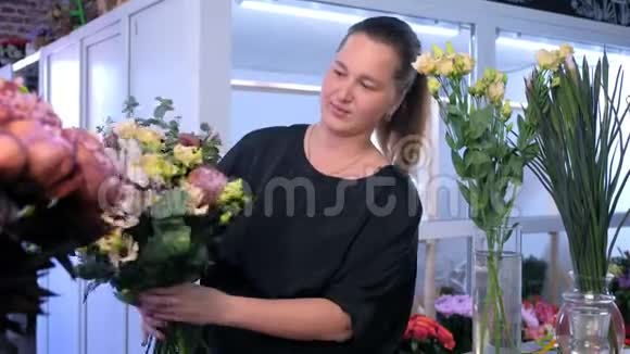 花商女人做大花束微笑着看着花店里的相机视频的预览图