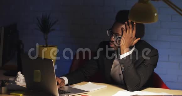 疲惫的年轻黑人商人在电脑屏幕前睡着了然后醒来继续工作视频的预览图