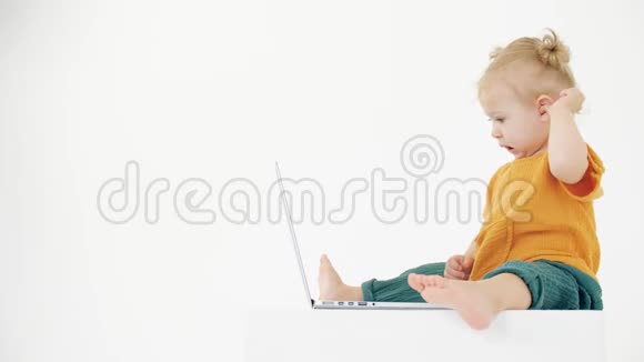 打哈欠的女婴看着白色背景上的笔记本电脑屏幕无聊内容相关剪辑视频的预览图
