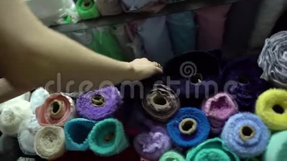 女性的手触摸着一大堆五颜六色的织物卷时尚柔软视频的预览图