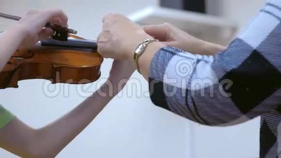 音乐老师教孩子在音乐学校拉小提琴双手特写视频的预览图