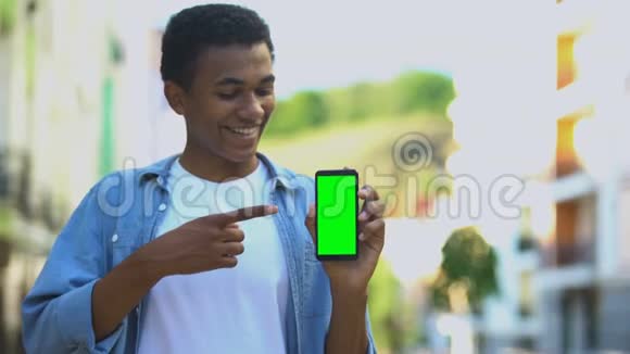 微笑少年手持绿屏智能手机导航应用视频的预览图