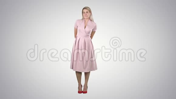 时尚笑脸的年轻美女模特在渐变背景下身着粉色连衣裙摆姿势的肖像视频的预览图