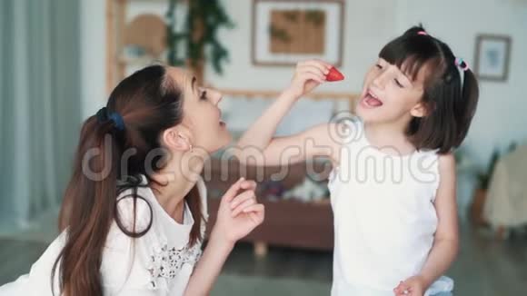 年轻的妈妈和可爱的小女儿吃草莓慢动作视频的预览图
