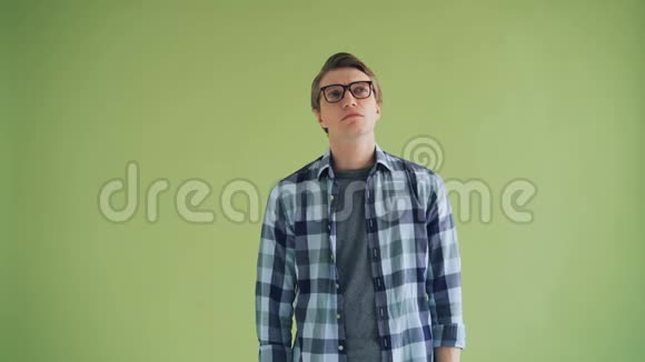 戴眼镜的体贴男人在绿色背景下看镜头的画像视频的预览图