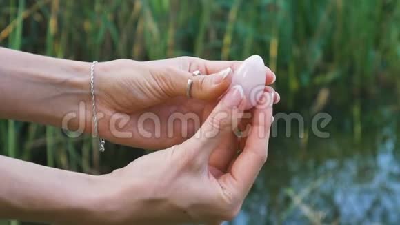 雌性手拿着玫瑰石英水晶玉蛋在河底妇女健康与自然观念的统一视频的预览图