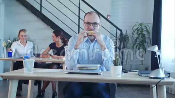 年轻的商人坐在办公室里吃三明治视频的预览图