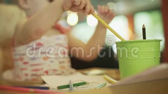 小女孩从桌上的水桶里拿出彩色铅笔视频的预览图
