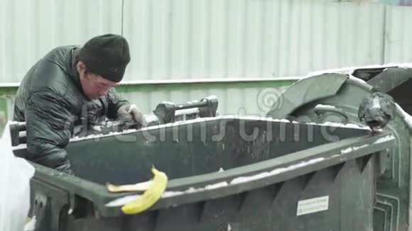 一个乞丐流浪汉正在垃圾桶里寻找食物基辅乌克兰视频的预览图