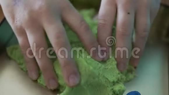 一个女孩的手在室内用海星模型玩绿色运动沙视频的预览图