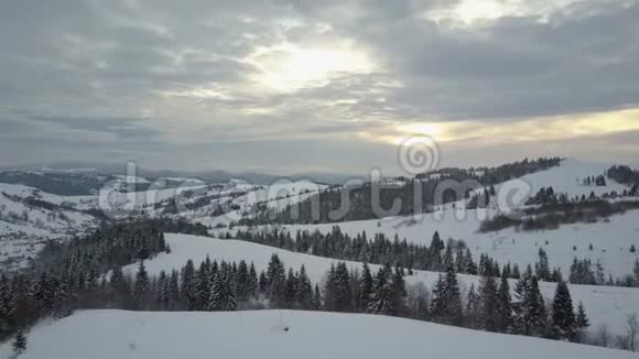 日出时飞越喀尔巴阡山的一个村庄鸟山上白雪覆盖的房子的视野农村视频的预览图