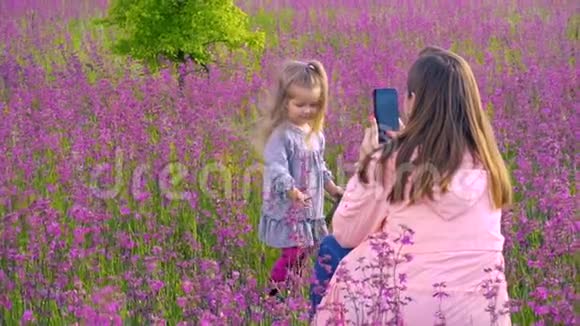 在田野里给女儿拍照的女人视频的预览图