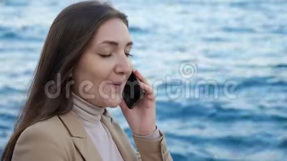 女士在海岸与模糊的海洋进行电话交谈视频的预览图