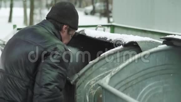 一个乞丐流浪汉正在垃圾桶里寻找食物基辅乌克兰视频的预览图