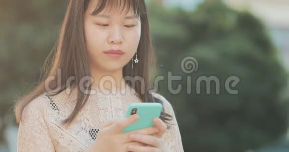 漂亮的亚洲女人用手机视频的预览图